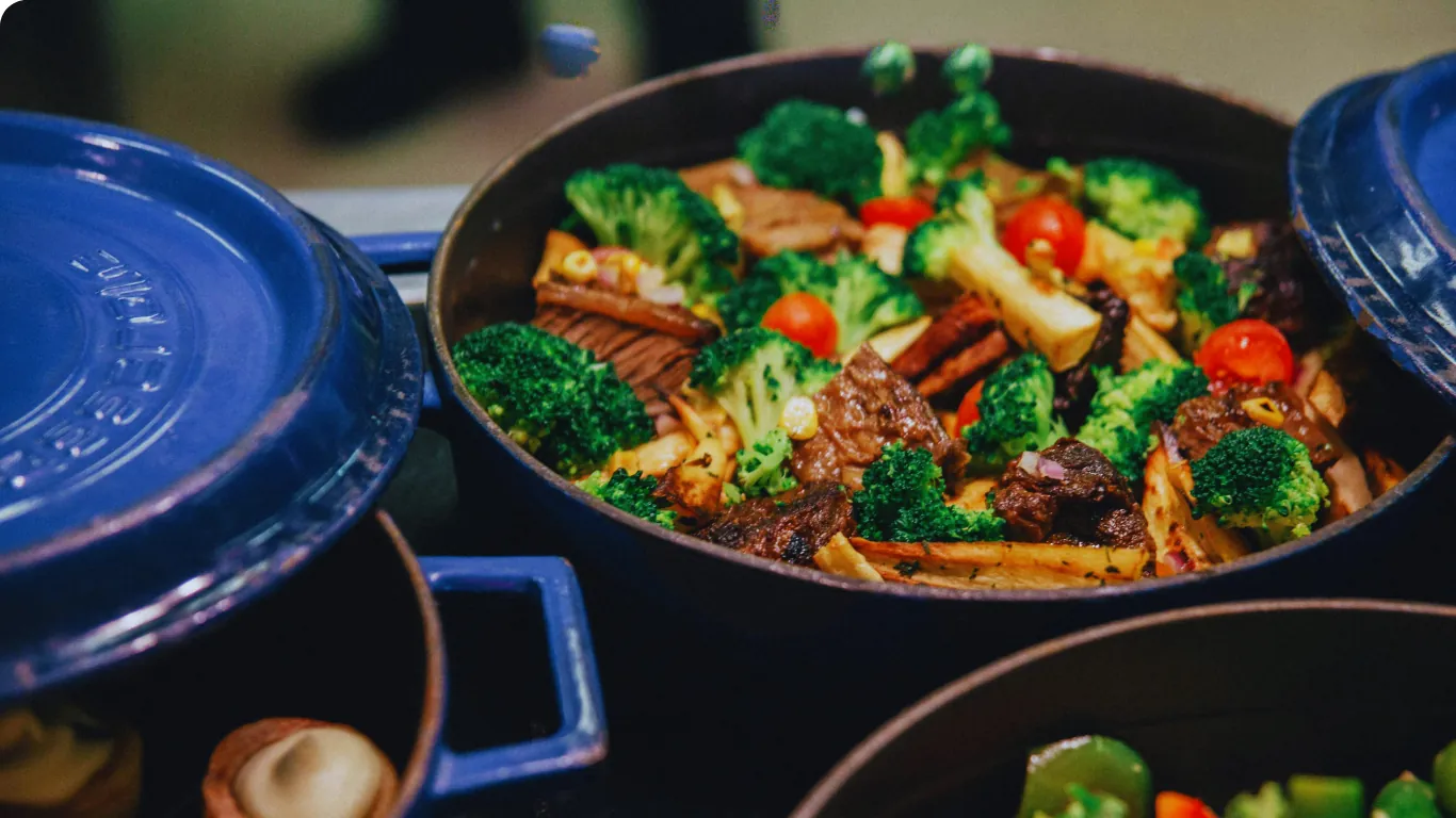 A cast-iron pot of braised beef with broccoli, tomatoes and root vegetables