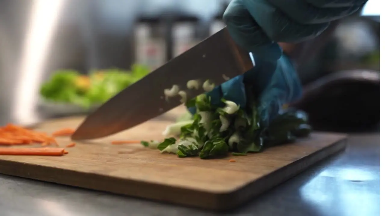 Chef Claire's hands finely chopping fresh herbs on a wooden board